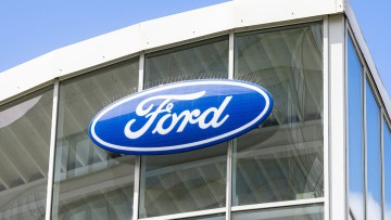Logo von Ford an der Glasfassade eines Autohauses 
