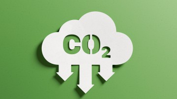 Eine weiße Wolke mit grünen Pfeilen symbolisiert die Reduzierung von CO2.