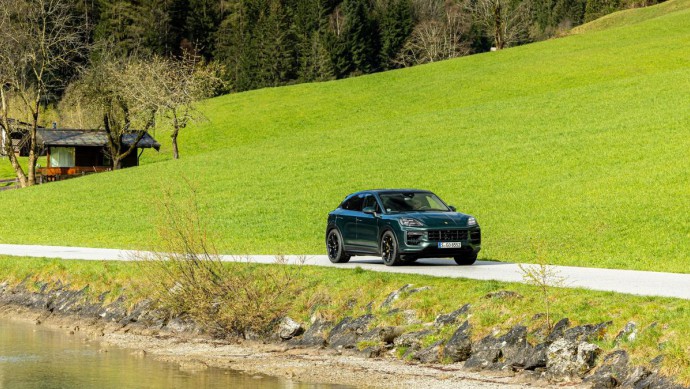 Porsche Cayenne S Coupé in Sonderlackierung Racinggreen auf Asphaltstraßen fahrend vor grüner Wiese in Tirol